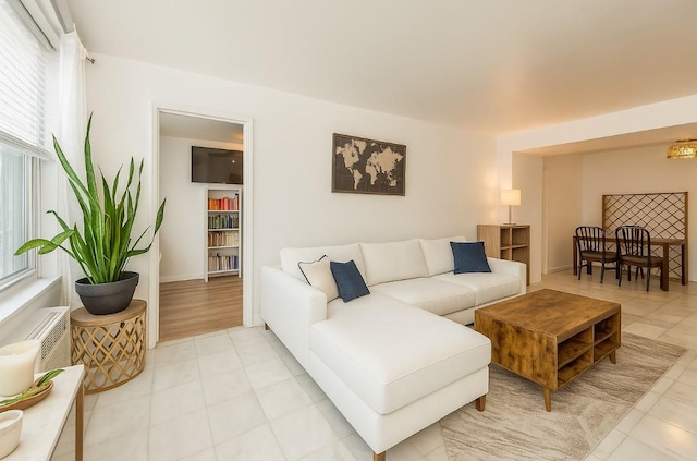 living area with healthy amount of natural light, light tile patterned floors, and baseboards