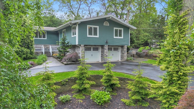 7 Tuxedo Dr, Melville, NY 11747 - view of front of house featuring stone siding, driveway, and an attached garage