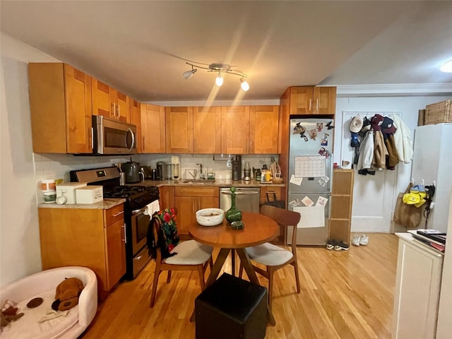 305 W 18th St Unit 1C, New York Manhattan, NY 10011 - kitchen with appliances with stainless steel finishes, a sink, light wood finished floors, and brown cabinetry