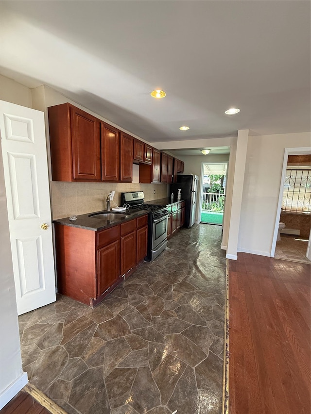 114-02 208th St, Saint Albans, NY 11411 - kitchen featuring stainless steel gas range, freestanding refrigerator, a sink, dark countertops, and baseboards