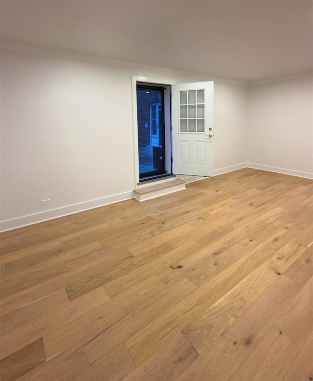 unfurnished room featuring light wood-type flooring, baseboards, and ornamental molding