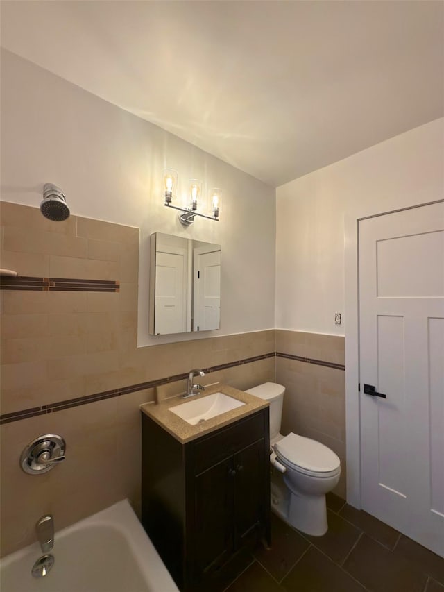 bathroom featuring tile walls, tile patterned floors, toilet, vanity, and tub / shower combination