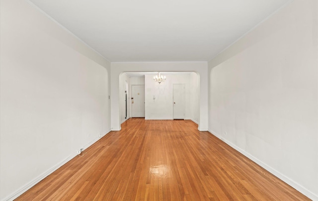 67-71 Yellowstone Blvd Unit 3-L, Forest Hills, NY 11375 - unfurnished room featuring a chandelier, arched walkways, light wood-type flooring, and baseboards