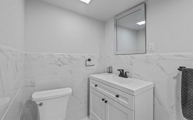 94 Stonehurst Ln, Dix Hills, NY 11746 - half bathroom with tile walls, vanity, toilet, and wainscoting