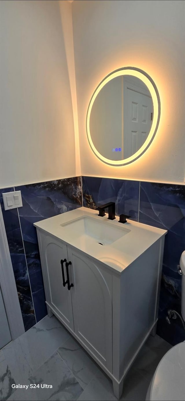 151 Boylston St, Hempstead, NY 11550 - bathroom featuring tile walls, marble look tiles, toilet, a wainscoted wall, and vanity