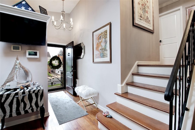 foyer with stairway, a chandelier, wood finished floors, and baseboards