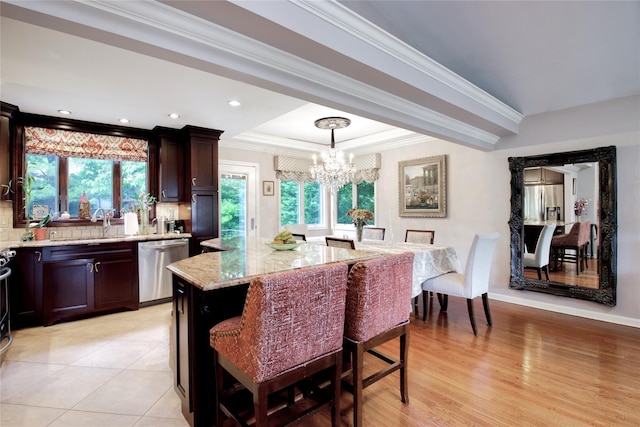 kitchen with dishwasher, a chandelier, light stone countertops, crown molding, and a kitchen island