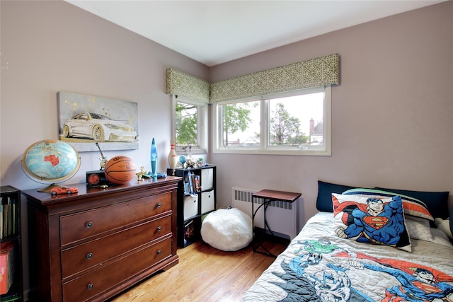 bedroom featuring radiator heating unit and light wood-style floors