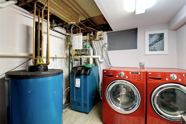 clothes washing area with separate washer and dryer, water heater, wood finished floors, and a heating unit