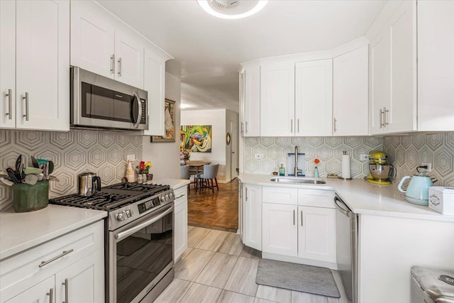 211-65 23rd Ave Unit 1B, Bayside, NY 11360 - kitchen featuring appliances with stainless steel finishes, a sink, light countertops, white cabinetry, and decorative backsplash