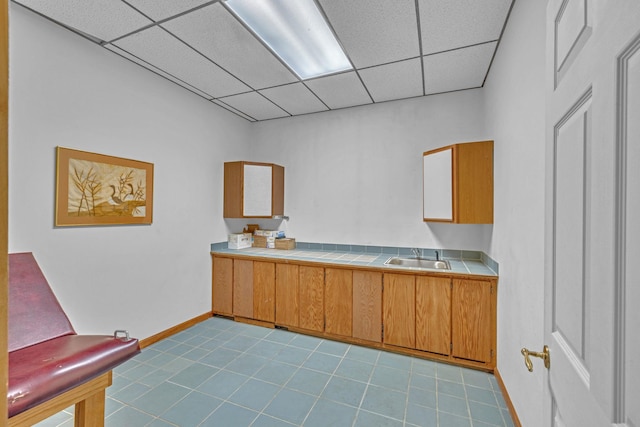 3893 Rte 82, Millbrook, NY 12545 - kitchen with tile countertops, a drop ceiling, tile patterned floors, brown cabinets, and a sink