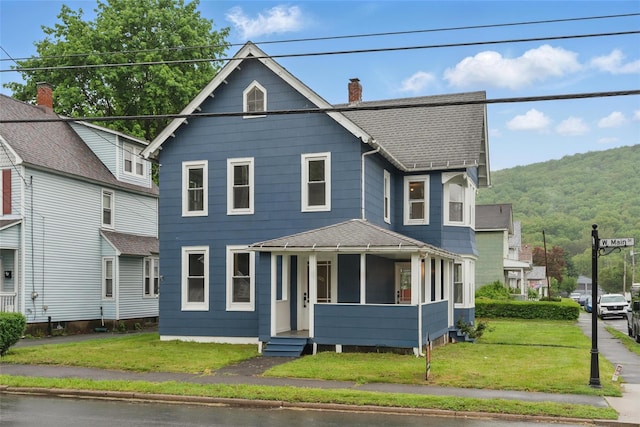 view of front of house featuring roof with shingles, a front lawn, and a chimney