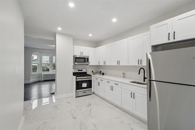 kitchen with stainless steel appliances, radiator heating unit, a sink, baseboards, and recessed lighting