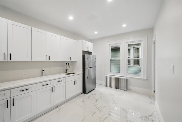 kitchen featuring radiator, freestanding refrigerator, a sink, baseboards, and recessed lighting