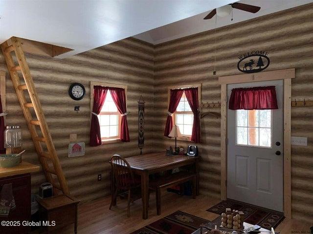 981 New Hague Rd, Call Listing Agent, NY 12836 - dining space featuring rustic walls, a ceiling fan, healthy amount of natural light, and wood finished floors