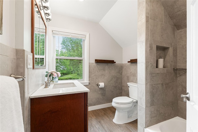 287 Harrison Ave, Harrison, NY 10528 - bathroom featuring tile walls, vanity, wood finished floors, vaulted ceiling, and a wainscoted wall