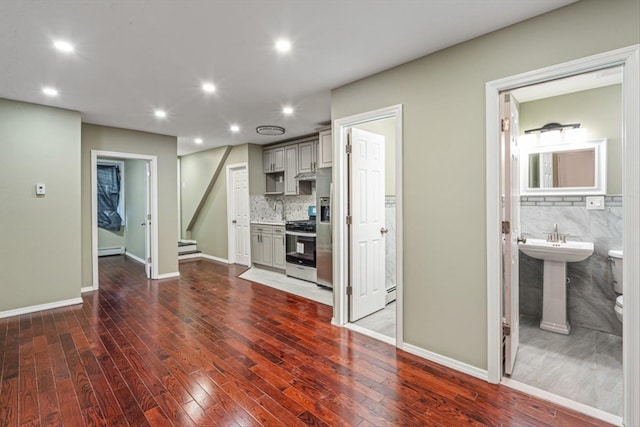107-30 156th St, Jamaica, NY 11433 - unfurnished living room featuring dark wood-type flooring, recessed lighting, baseboard heating, a sink, and baseboards