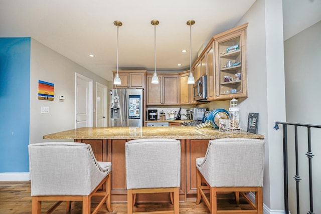 kitchen with stainless steel appliances, light wood finished floors, a peninsula, baseboards, and hanging light fixtures