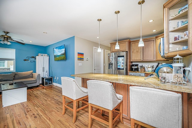 kitchen featuring appliances with stainless steel finishes, a peninsula, light wood-type flooring, decorative light fixtures, and recessed lighting