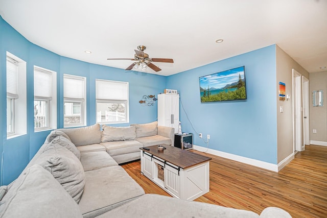living area featuring ceiling fan, baseboards, light wood-type flooring, plenty of natural light, and recessed lighting
