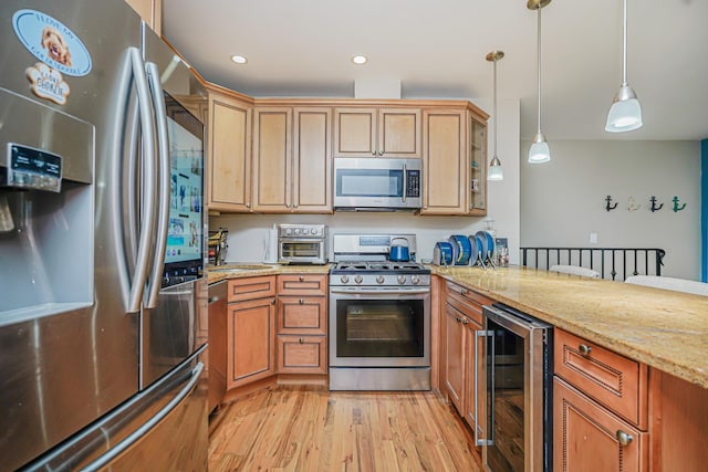 kitchen with appliances with stainless steel finishes, beverage cooler, light wood-type flooring, hanging light fixtures, and a peninsula