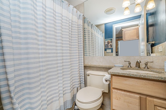 bathroom with tile walls, vanity, toilet, and backsplash
