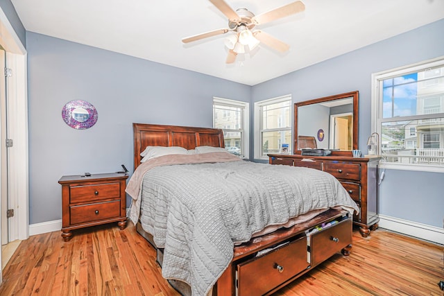 bedroom featuring baseboards, wood finished floors, multiple windows, and a ceiling fan