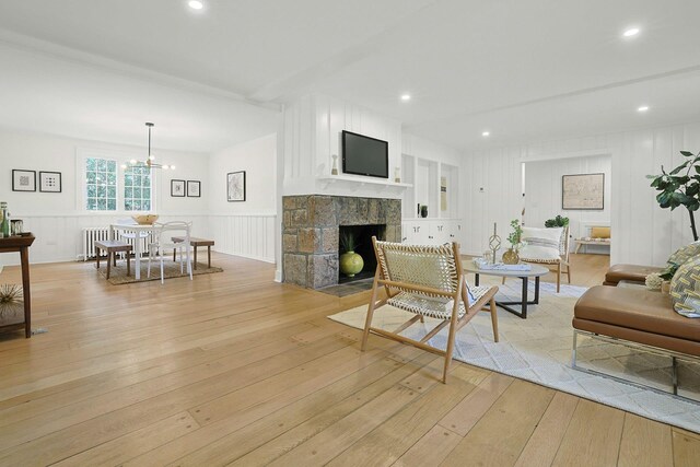 92 Glenwood Ave, New Rochelle, NY 10801 - living area with radiator heating unit, light wood-style flooring, a decorative wall, a stone fireplace, and a wainscoted wall