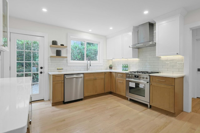 92 Glenwood Ave, New Rochelle, NY 10801 - kitchen with stainless steel appliances, wall chimney range hood, light wood-style flooring, light countertops, and plenty of natural light