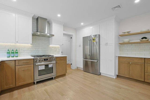 92 Glenwood Ave, New Rochelle, NY 10801 - kitchen featuring high quality appliances, wall chimney range hood, light countertops, decorative backsplash, and light wood finished floors
