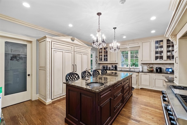 7 Ridgeview Cir, Armonk, NY 10504 - kitchen featuring cream cabinets, a chandelier, range with two ovens, dark brown cabinetry, and a center island with sink