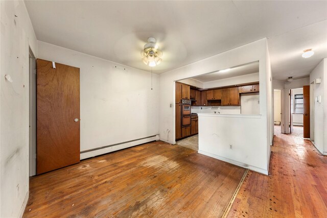 71-34 Kissena Blvd, Flushing, NY 11367 - kitchen with ceiling fan, oven, a baseboard heating unit, light wood finished floors, and a peninsula