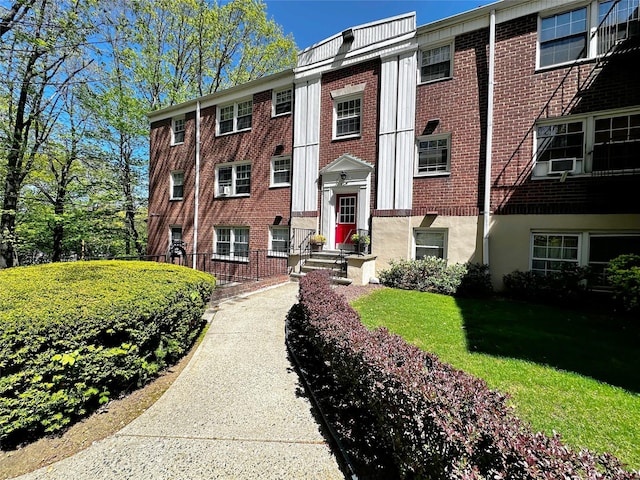 view of front of home featuring brick siding, a front lawn, and cooling unit