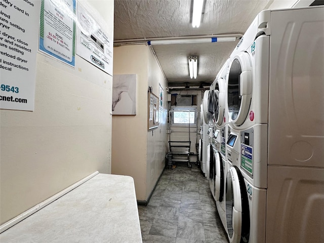 community laundry room with estacked washer and dryer, a garage, baseboards, and washer and clothes dryer