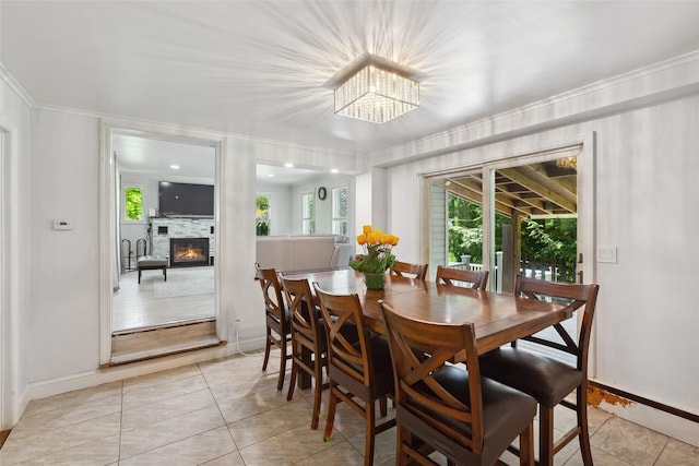 21 Wagon Ln, Brewster, NY 10509 - dining room featuring a glass covered fireplace, healthy amount of natural light, light tile patterned floors, baseboards, and crown molding