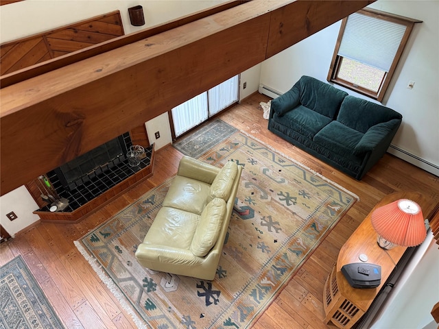 living room with a baseboard heating unit, wood-type flooring, and a fireplace