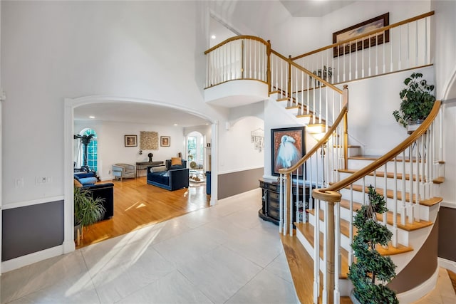 1 Pitch Pine Ct, Northport, NY 11768 - foyer entrance featuring arched walkways, a towering ceiling, stairs, tile patterned floors, and baseboards