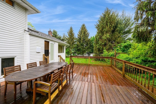 deck with outdoor dining space and view of wooded area