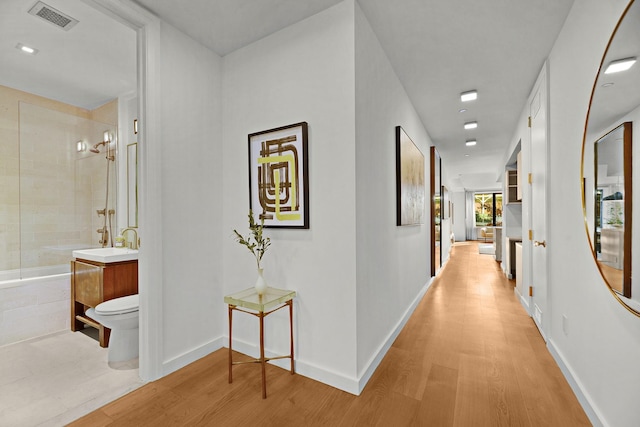212 E 95th St, New York Manhattan, NY 10128 - hallway with light wood-style floors, baseboards, and a sink