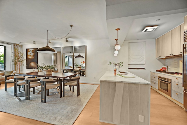 212 E 95th St, New York Manhattan, NY 10128 - kitchen featuring stainless steel oven, light wood-style floors, light stone counters, backsplash, and hanging light fixtures