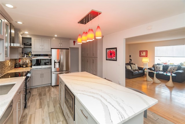 129 Boardman Rd, Poughkeepsie, NY 12603 - kitchen with stainless steel appliances, a center island, light wood-style floors, open floor plan, and light stone counters