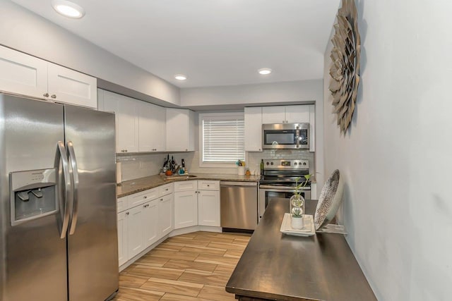 51 Andrews Ave, Wyandanch, NY 11798 - kitchen featuring appliances with stainless steel finishes, white cabinets, backsplash, light wood-type flooring, and recessed lighting