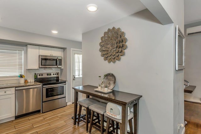 51 Andrews Ave, Wyandanch, NY 11798 - kitchen with appliances with stainless steel finishes, white cabinets, decorative backsplash, light wood-style floors, and dark stone counters