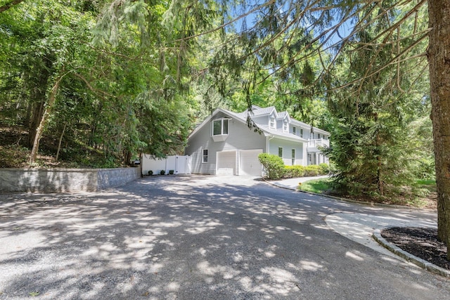 view of side of property with an attached garage, driveway, and fence