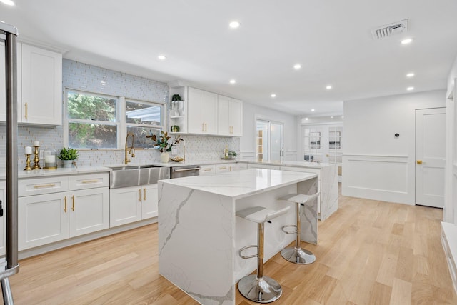 kitchen with a sink, a peninsula, decorative backsplash, light wood-style flooring, and recessed lighting