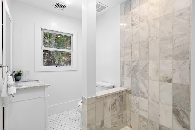 bathroom with toilet, vanity, and a tile shower