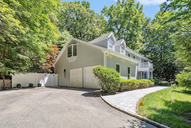 view of side of property featuring asphalt driveway, fence, and a garage