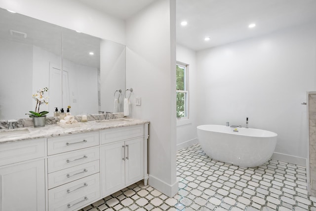 full bathroom featuring baseboards, a freestanding bath, double vanity, and recessed lighting