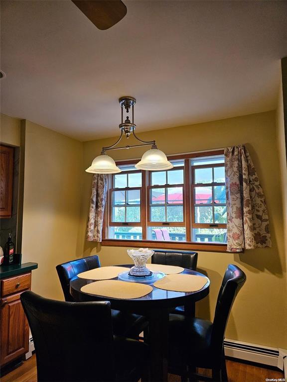 dining area with a baseboard heating unit and wood finished floors