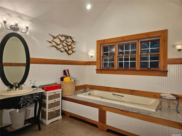 bathroom with a sink, a wainscoted wall, tile patterned flooring, lofted ceiling, and a bath